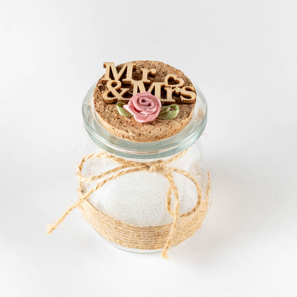 Μπομπονιέρα σε γυάλινο βαζάκι με φελό διακοσμημένη με ξυλινο MR&MRS και mini τριανταφυλλάκι